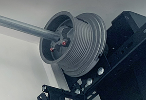 Close view of residential garage door cable, drum,, track and spring